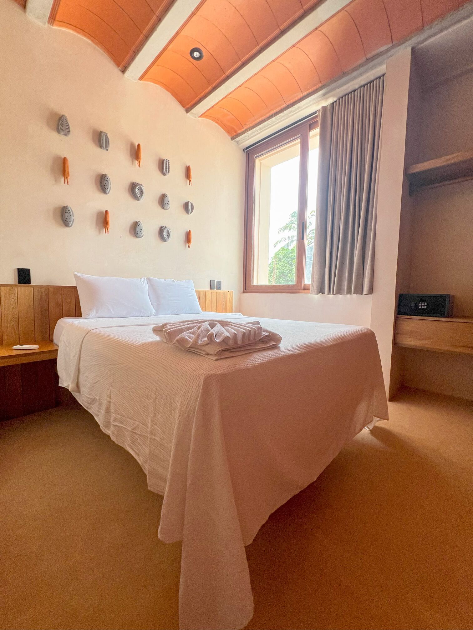 Un dormitorio con una cama grande, cabecera de madera, un reloj de pared y una ventana con cortinas.