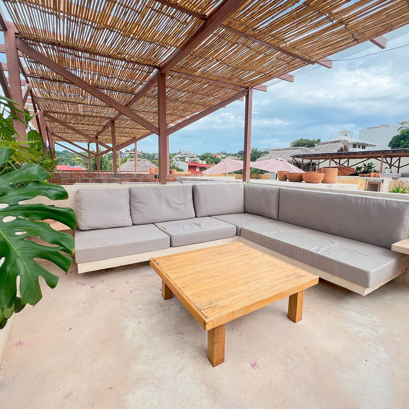 A covered outdoor seating area with a sectional sofa and a wooden coffee table.
