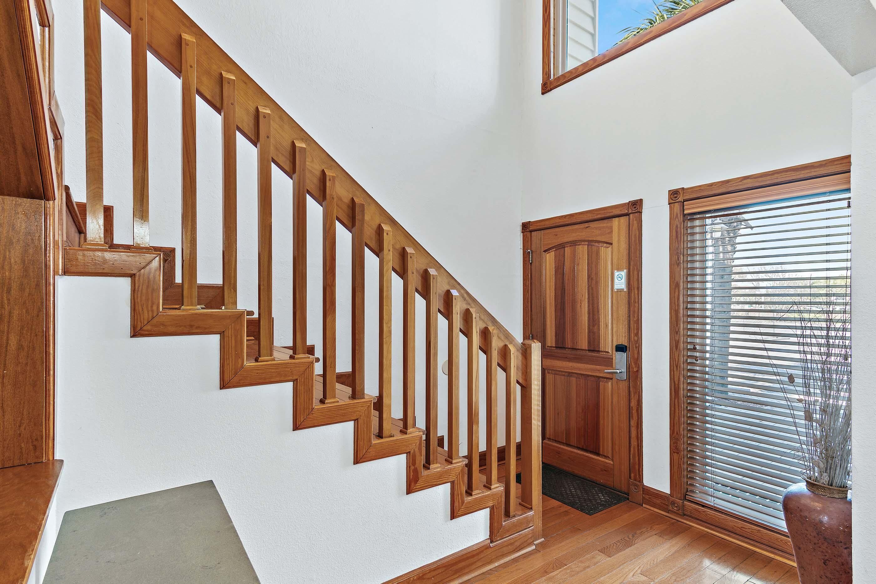 A wooden staircase with a handrail, a wooden door, and a window with blinds.