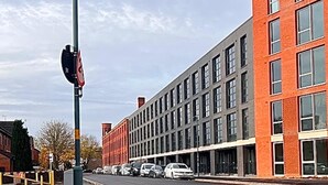 Ein mehrstöckiges Gebäude mit modernem architektonischen Design, das Ziegel- und Glasfassaden kombiniert.