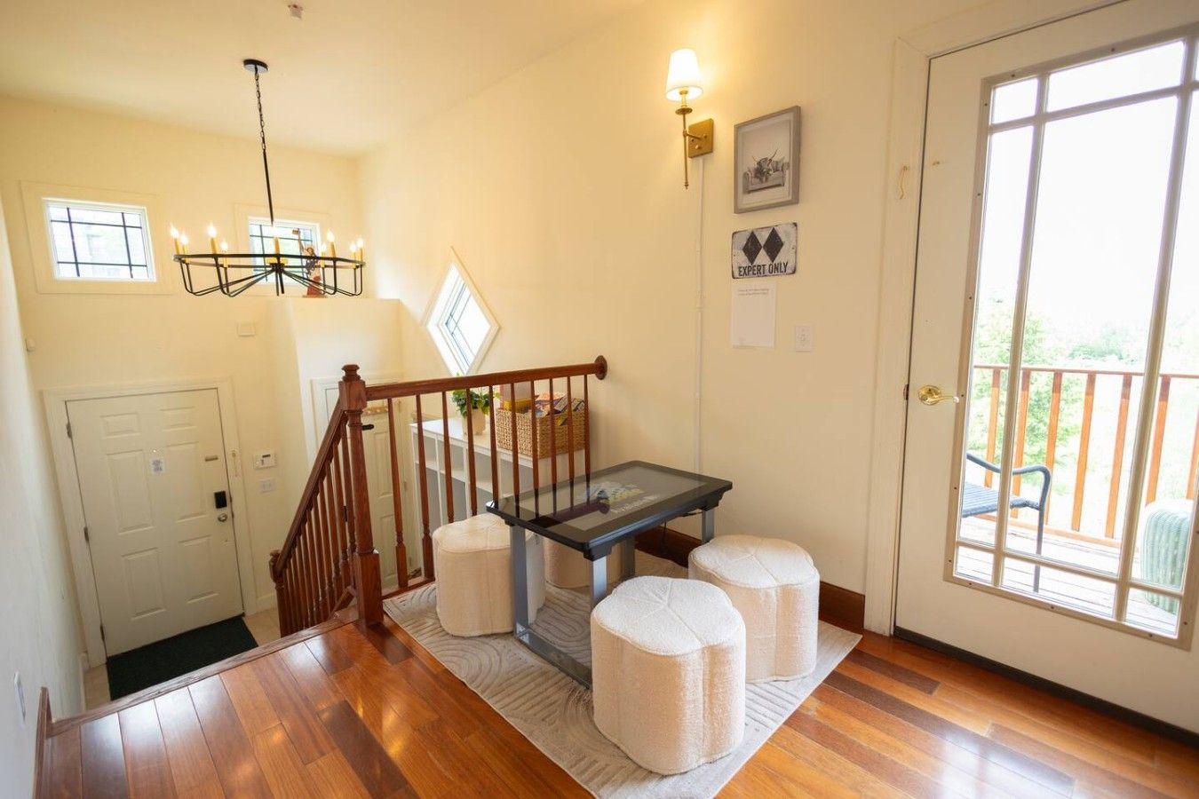 A staircase with a wooden handrail leading to a landing with a table and ottomans.