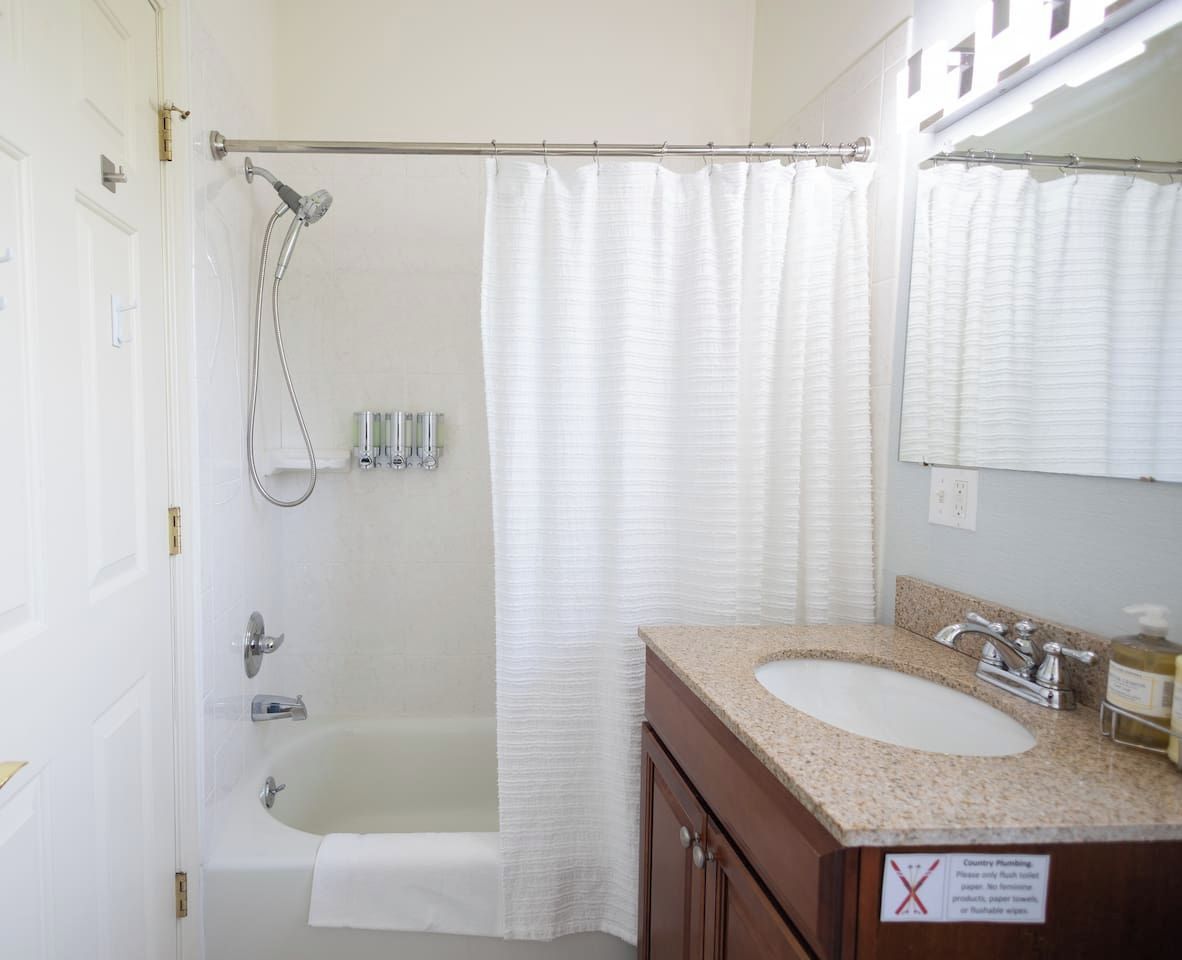 A bathroom with a bathtub, a shower, a sink, and a mirror.