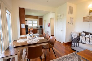 A dining area with a wooden table, chairs, and a kitchen in the background.