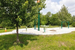 A park with exercise equipment, a tree, and a grassy area.