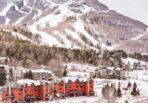 A ski resort with red buildings, snow-covered slopes, and a mountainous backdrop.