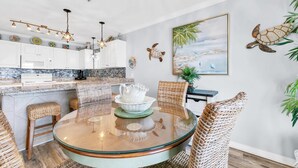 A modern kitchen with white cabinets, a granite countertop, and a hanging light fixture. - Gulf Place Caribbean 313- Sunsets on 30A (Santa Rosa Beach)