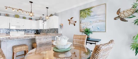A modern kitchen with white cabinets, a granite countertop, and a hanging light fixture.