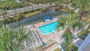 A resort with a swimming pool surrounded by palm trees, a water feature, and a view of the ocean. - Gulf Place Caribbean 313- Sunsets on 30A (Santa Rosa Beach)