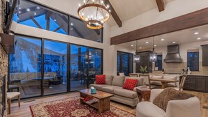 A spacious living area with a large window, a fireplace, and a cozy seating arrangement. - Alpine Luxury | Engineer Mtn View | Pool & Hot Tub (Durango)