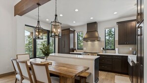A modern kitchen with a central island, dark cabinetry, and a hanging light fixture. - Alpine Luxury | Engineer Mtn View | Pool & Hot Tub (Durango)