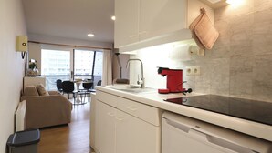 Une cuisine moderne avec des meubles blancs, un plan de travail noir et une machine à café rouge.