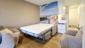 Une chambre à coucher de taille réduite, comprenant un lit, un petit bureau et une chaise.