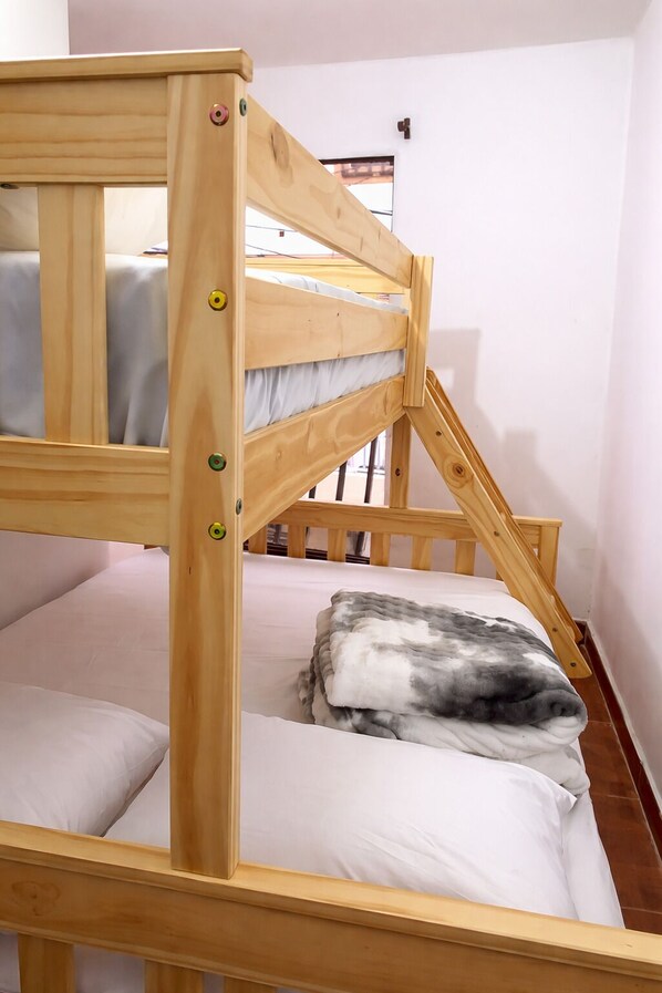 Una litera con estructura de madera y un colchón con almohada.