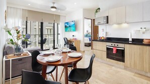 A modern kitchen with wooden cabinets, a black countertop, and a stainless steel oven. - Stylish 2Bd Condo, Rooftop Oasis in Playa del Carmen (Playa Del Carmen)