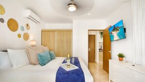 A modern bedroom with a bed, bedside table, and a TV mounted on the wall. - Stylish 2Bd Condo, Rooftop Oasis in Playa del Carmen (Playa Del Carmen)