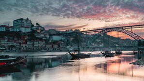 A river with boats, a bridge, and buildings in the background. - Modern Apartment in Porto's Vibrant Heart (Porto)