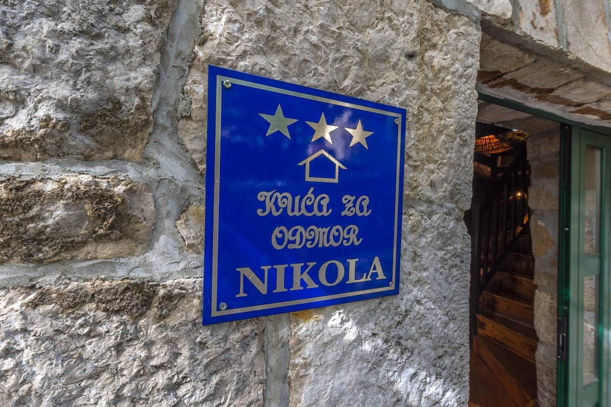 A blue sign with gold lettering and stars, mounted on a stone wall.