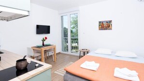 Une chambre d’hôtel moderne équipée d’un lit, d’un bureau, d’une télévision et d’un balcon avec vue.