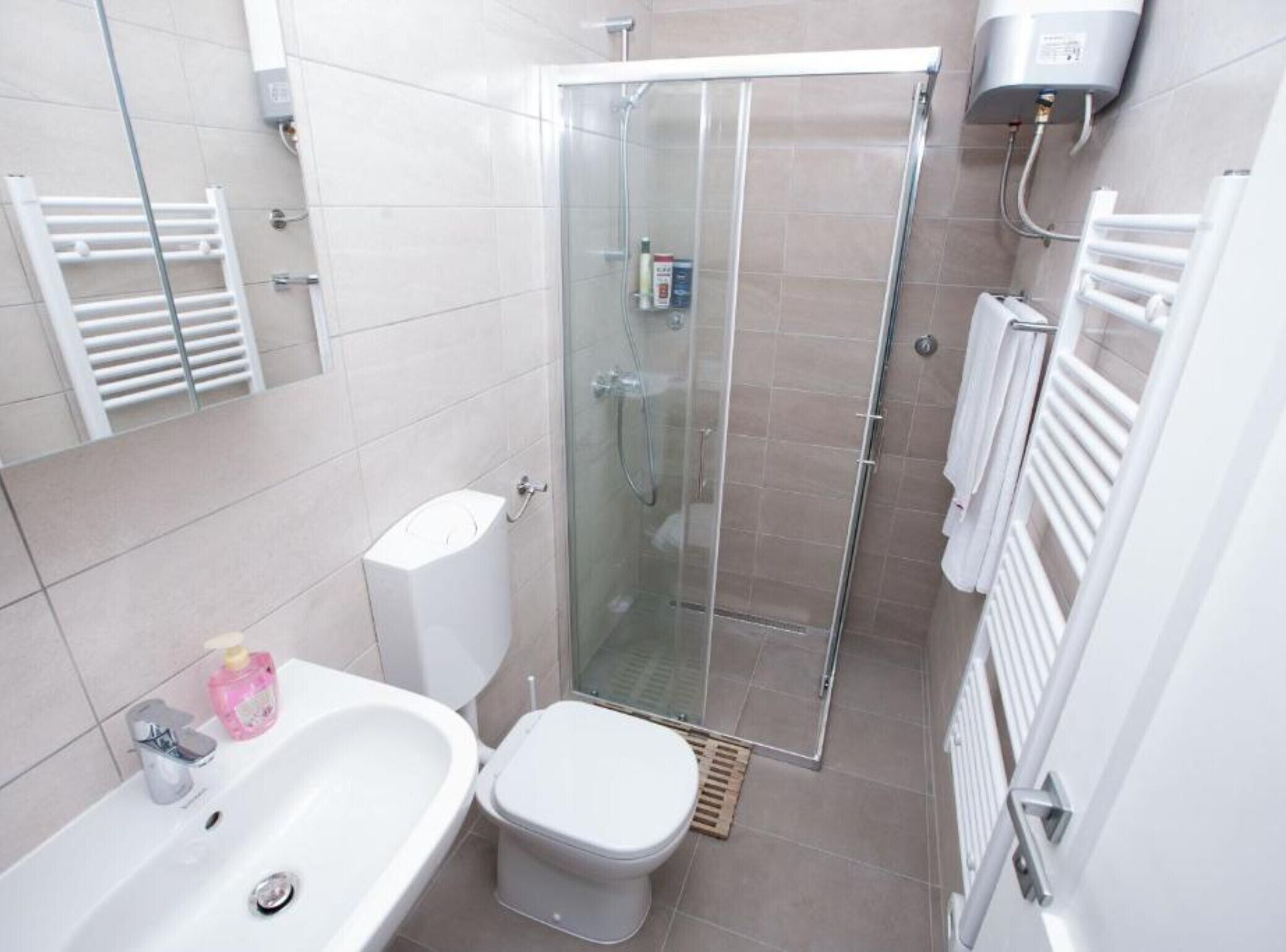 A modern bathroom with a glass-enclosed shower, a white bathtub, and a toilet.