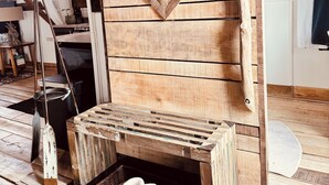 Ein rustikaler Holzraum mit einer Bank, einem Kamin und einem Korb mit Hausschuhen.