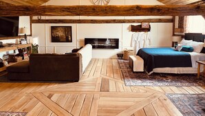 Ein gemütliches Zimmer mit Holzbalkendecke, einem großen Bett, einem Fernseher und einem Kamin.