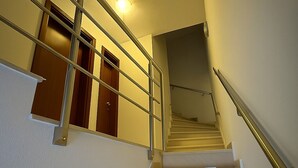 A staircase with a metal handrail and wooden doors at the top.