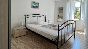 A bedroom with a bed, bedside table, and a window with curtains.