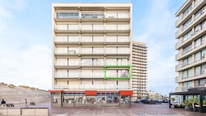 Een hotel met meerdere verdiepingen, een plat gevelvlak, grote ramen en een restaurant op de begane grond met terrasplaatsen.
