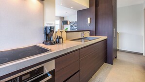 Een moderne keuken met een inbouwfornuis, een dubbele spoelbak en een grote spiegel boven het aanrecht.