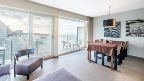 Een moderne hotelkamer met een balkon, een eethoek en kunstwerken aan de muur.
