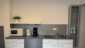 Una cucina compatta con forno a microonde, macchina del caffè e lavello.