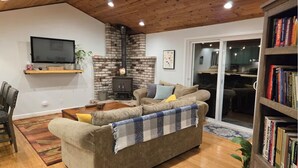 Ein gemütliches Wohnzimmer mit Kamin, einer Couch, einem Fernseher und einem Bücherregal.