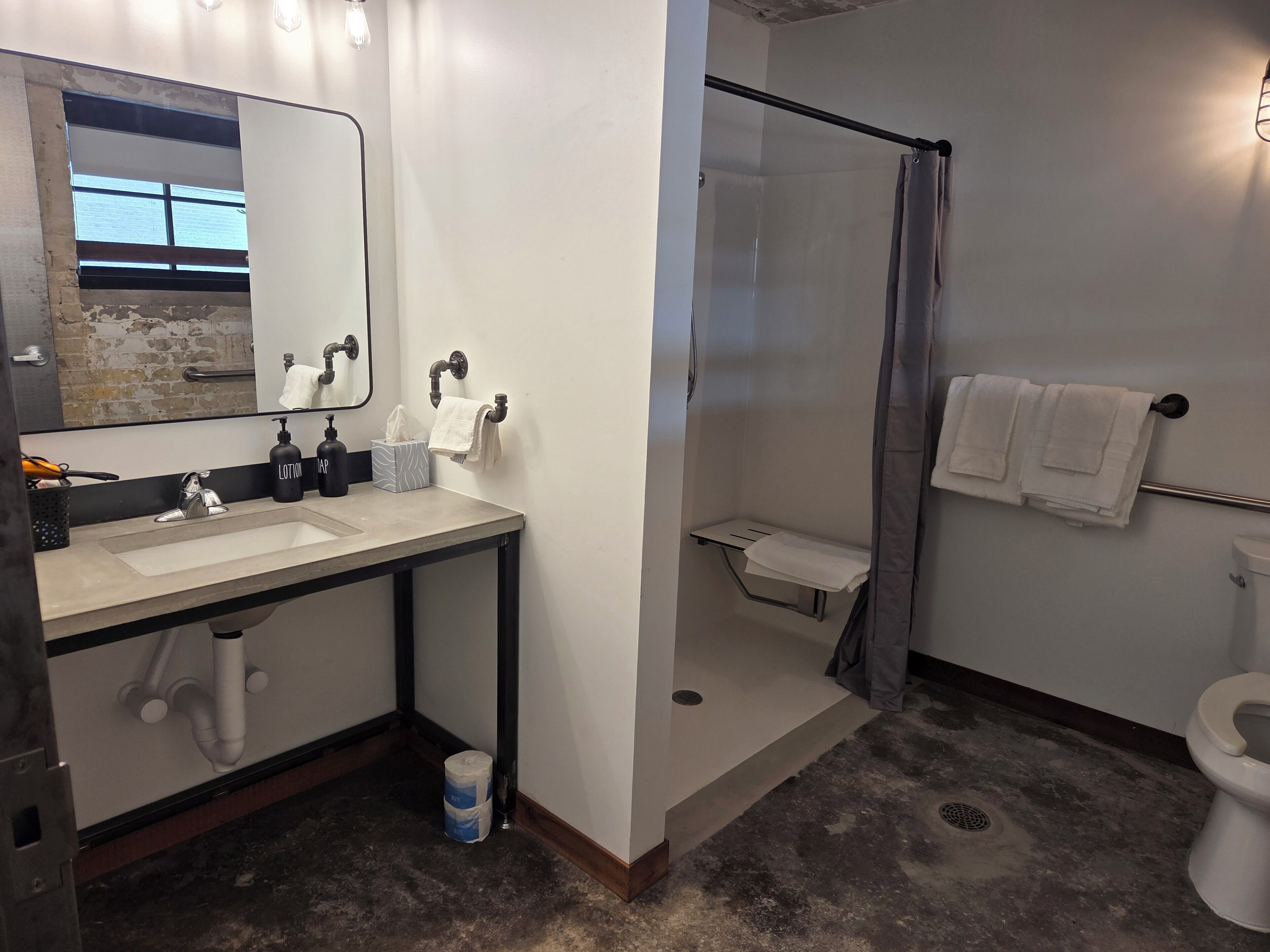 A bathroom with two sinks, a mirror, a shower, and a toilet.