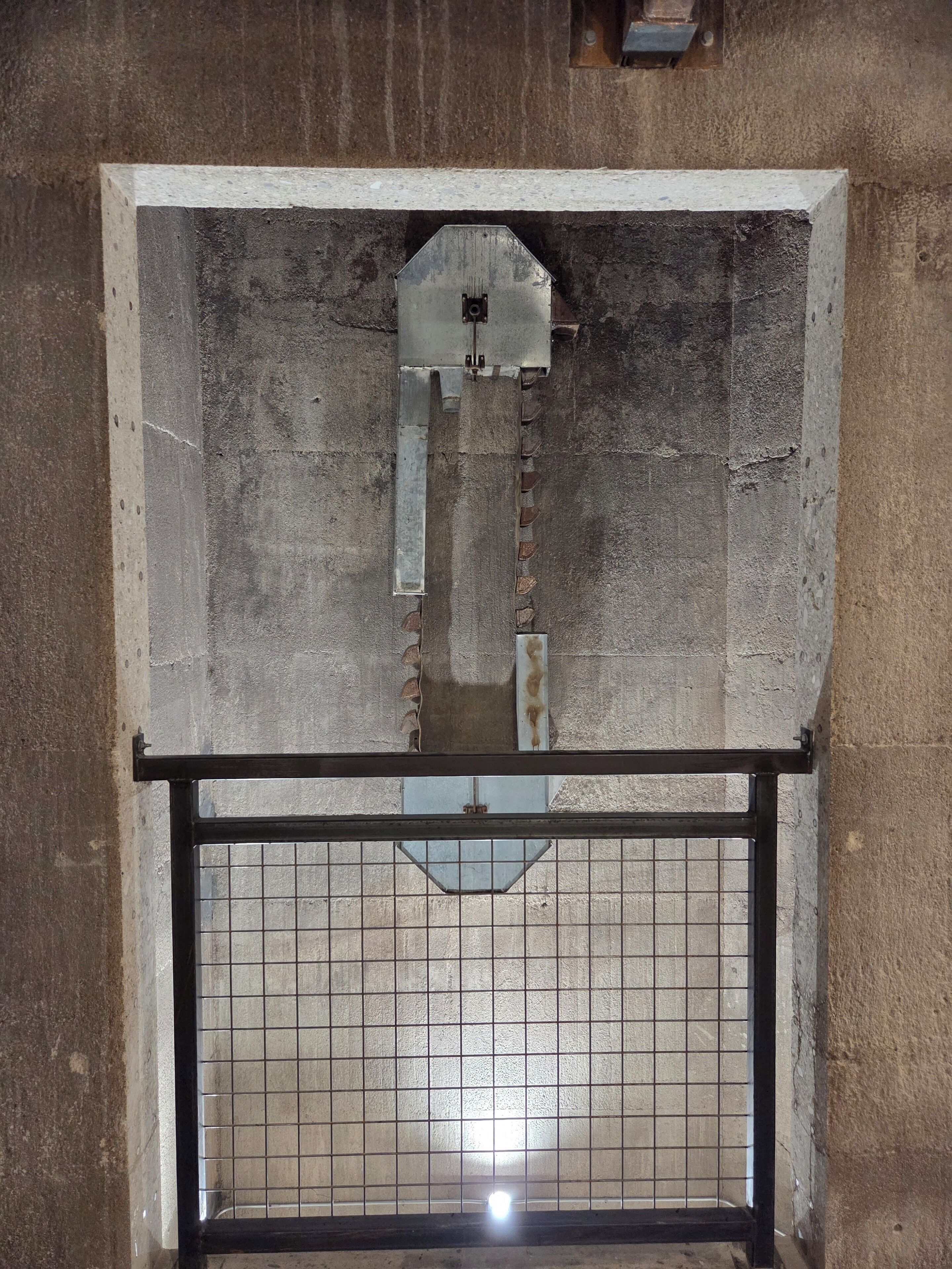 Una ventana con una reja metálica y un elemento metálico central.