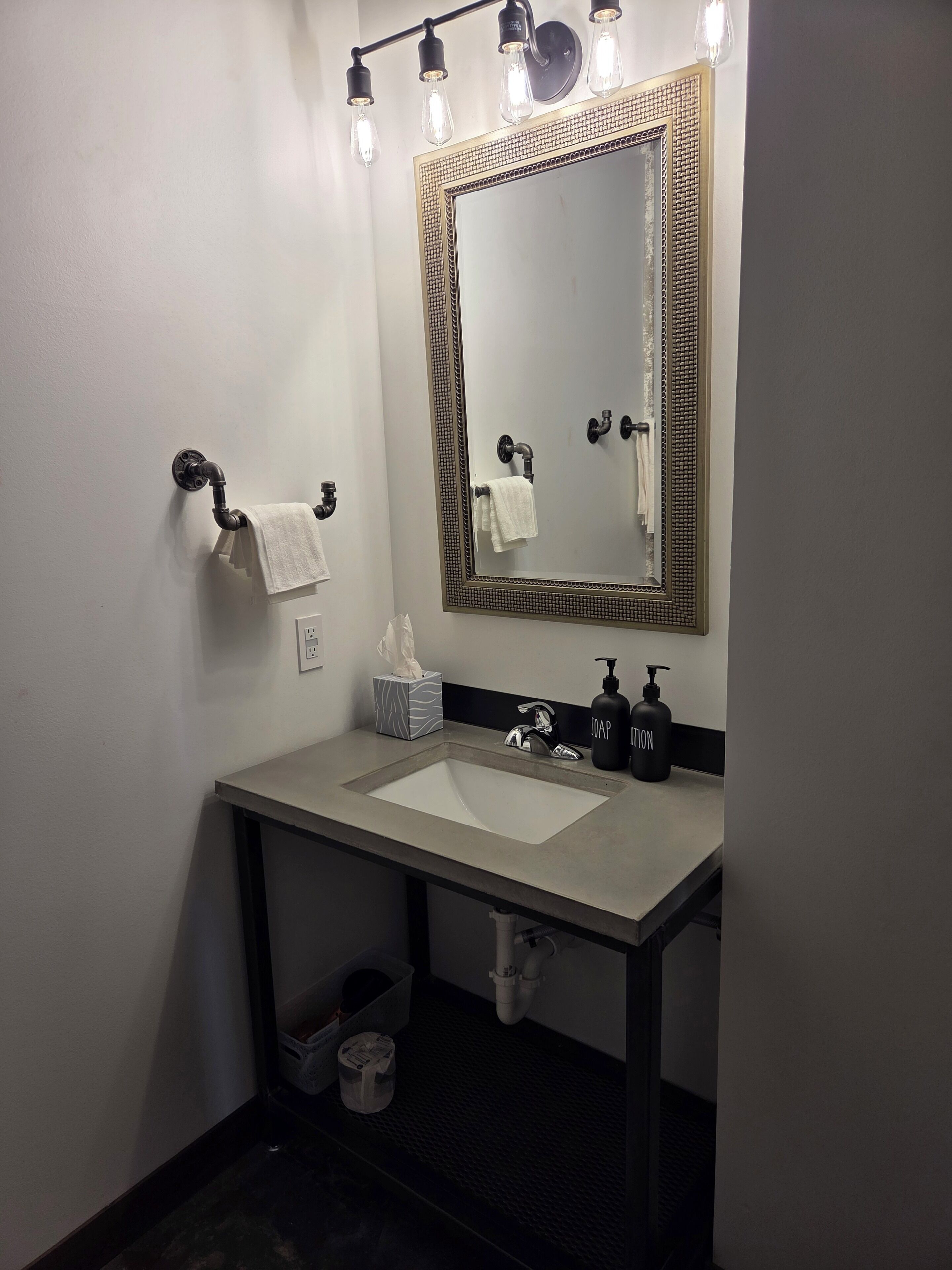 A bathroom with a large mirror, a sink, and a towel rack.