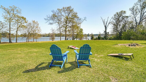 Zwei Adirondack-Stühle mit Blick auf einen See, im Hintergrund ein Picknicktisch und ein Kanu.
