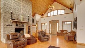 A spacious living room with a fireplace, leather recliners, a large rug, and a high ceiling with wooden beams. - 366 Shared Acres, Lake Access: Ozark Getaway! (Shirley)