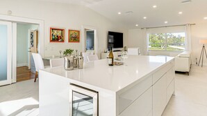 A modern kitchen with a large island, white cabinetry, and a flat-screen TV. - 3 Mi to Beach: Pet-Friendly Home in Port Charlotte (Port Charlotte)