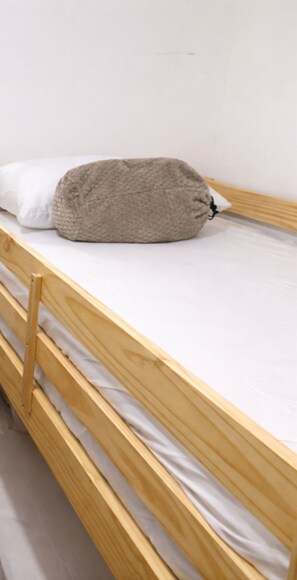 Un lit superposé en bois, avec un matelas et un oreiller.