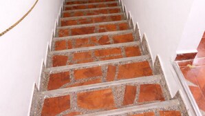 Una escalera de ladrillos rojos y paredes blancas que conduce a una puerta negra.