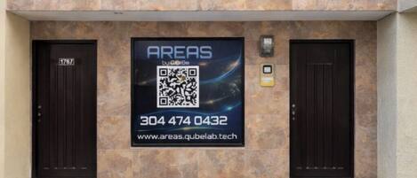 Een gevel met twee borden die 'AREAS by QuBe Lab' adverteren en een QR-code.