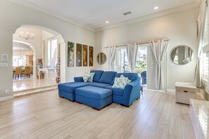 Relax in this stylish living room with a large sofa, dining area, and high ceiling.