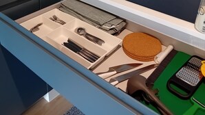 A kitchen drawer with utensils, a cutting board, and a grater.