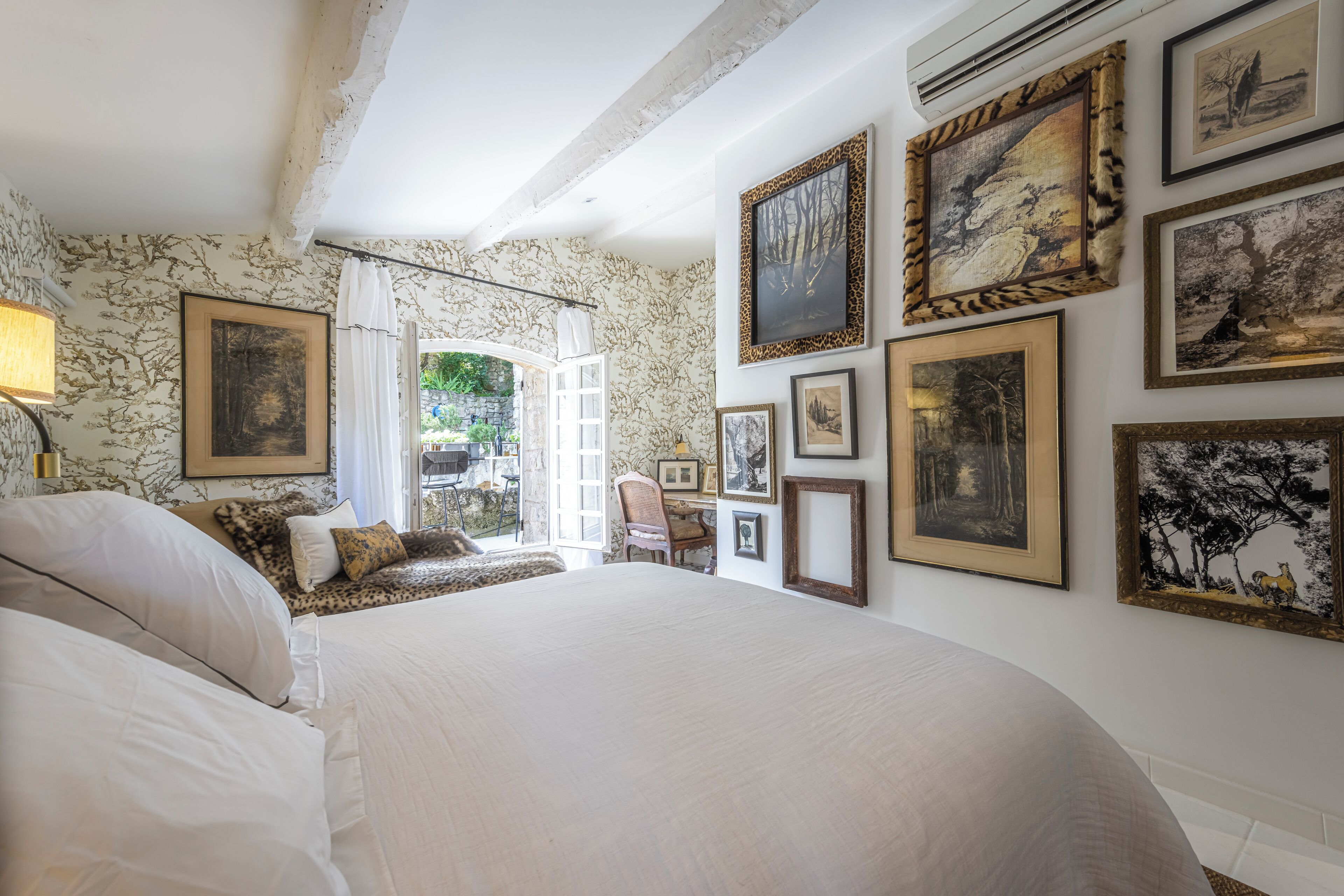 Une chambre avec un grand lit, un bureau et plusieurs tableaux encadrés accrochés aux murs.