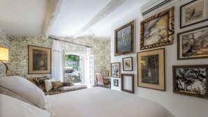 A bedroom with a large bed, a desk, and multiple framed pictures on the walls.