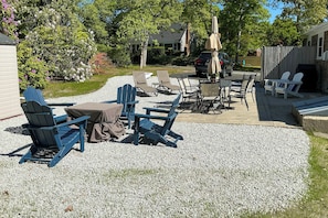Un espace extérieur aménagé avec des chaises Adirondack et une table, entouré d’une terrasse en gravier.