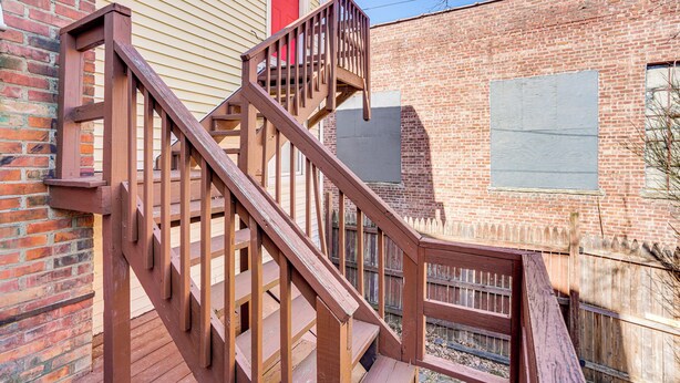 A wooden staircase leading to a red door, a brick wall, and a window with a shutter. - Walk to Dtwn Hudson: Cozy Upstate Apartment (Hudson)