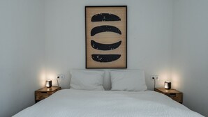 Un dormitorio con una cama, dos mesitas de noche y una obra de arte colgada en la pared.