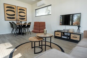 A modern living room with a dining area, a sofa, a TV, and a fireplace.