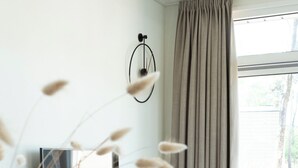 Una sala de estar moderna con un sofá, un televisor, una mesita auxiliar y un ventanal grande con cortinas.
